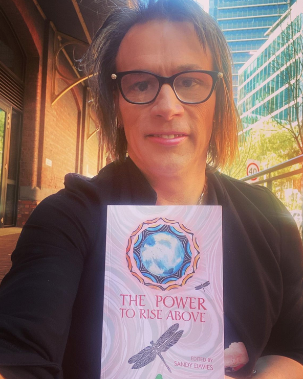 Melissa Griffiths holding a copy of book The Power to Rise Above